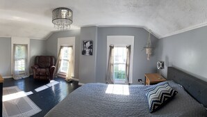 Une chambre avec un grand lit, une chaise, un bureau et une fenêtre.