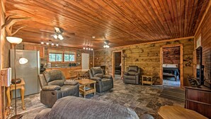 A log cabin interior with a living room, kitchen, and sleeping area.