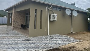 A modern house with a tiled roof, satellite dishes, and an air conditioning unit.