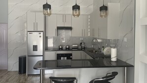 A modern kitchen with a marble backsplash, stainless steel appliances, and pendant lighting.