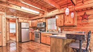 Une cuisine de style rustique, avec des éléments en bois, un îlot central, des appareils en acier inoxydable et un panneau d’accueil en forme d’étoile.
