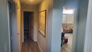 Un couloir au sol en bois, une porte sur la gauche et une carte encadrée accrochée au mur.