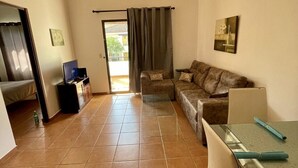 Una sala de estar amplia con un sofá, una mesa de vidrio y un ventilador de techo.