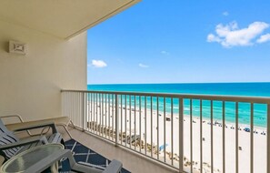 Ein Balkon mit Blick auf einen Strand, einem Tisch und Stühlen.