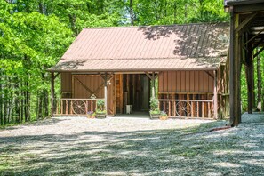 A rustic wooden building with a metal roof, surrounded by a forest.