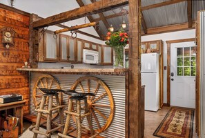 A rustic kitchen with wooden beams, a vintage refrigerator, and wooden stools.