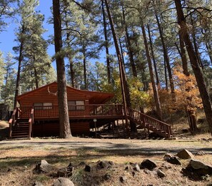 A cabin with a wooden deck and stairs leading to a covered porch. - 3 Little Bears - GREAT location; secluded feel! (Ruidoso)