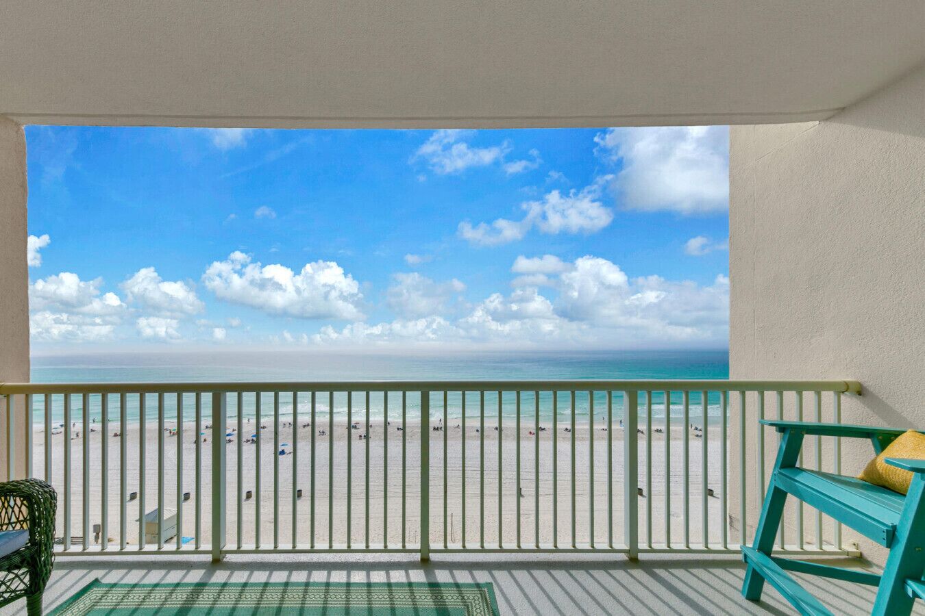 Een balkon met uitzicht op een strand, een stoel en een klein tafeltje.