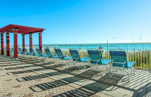 Enjoy the ocean views from the promenade's blue chairs, shaded by a pergola.