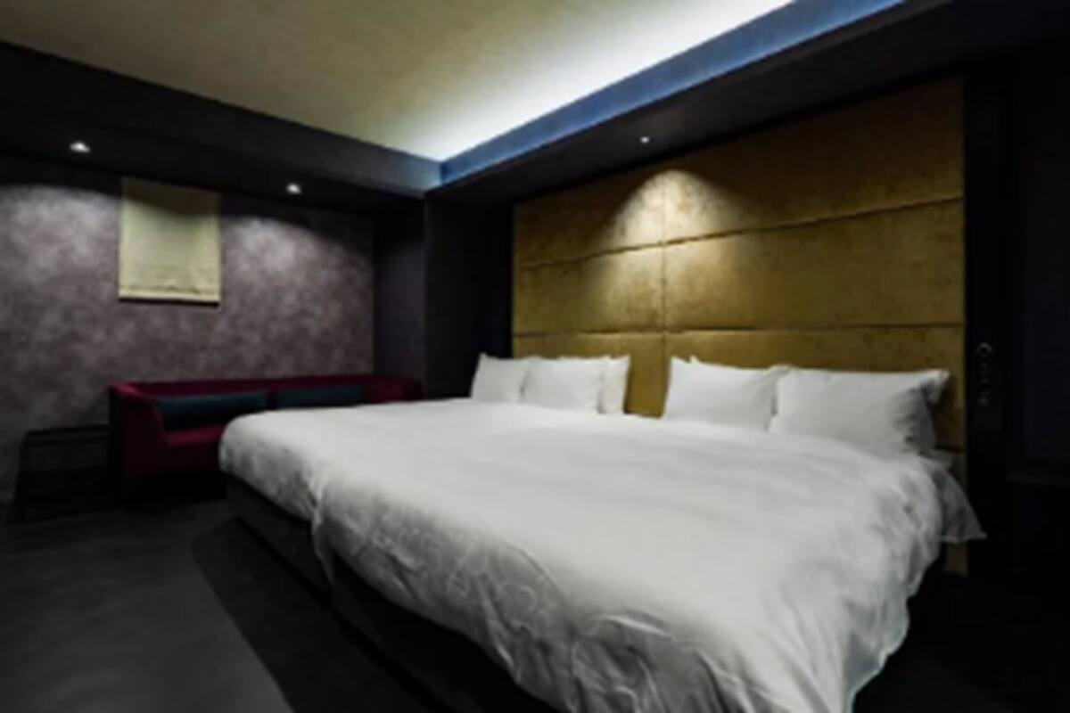 A modern hotel room with a large bed, a red bench, and a wooden headboard.
