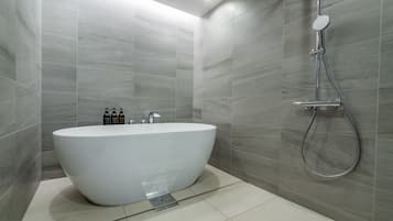 Un baño moderno con una bañera independiente, un cabezal de ducha de mano y un grifo empotrado.