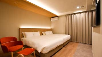Une chambre d’hôtel moderne avec un plafond en bois, un grand lit avec une literie blanche, un fauteuil rouge et un téléviseur à écran plat fixé au mur.