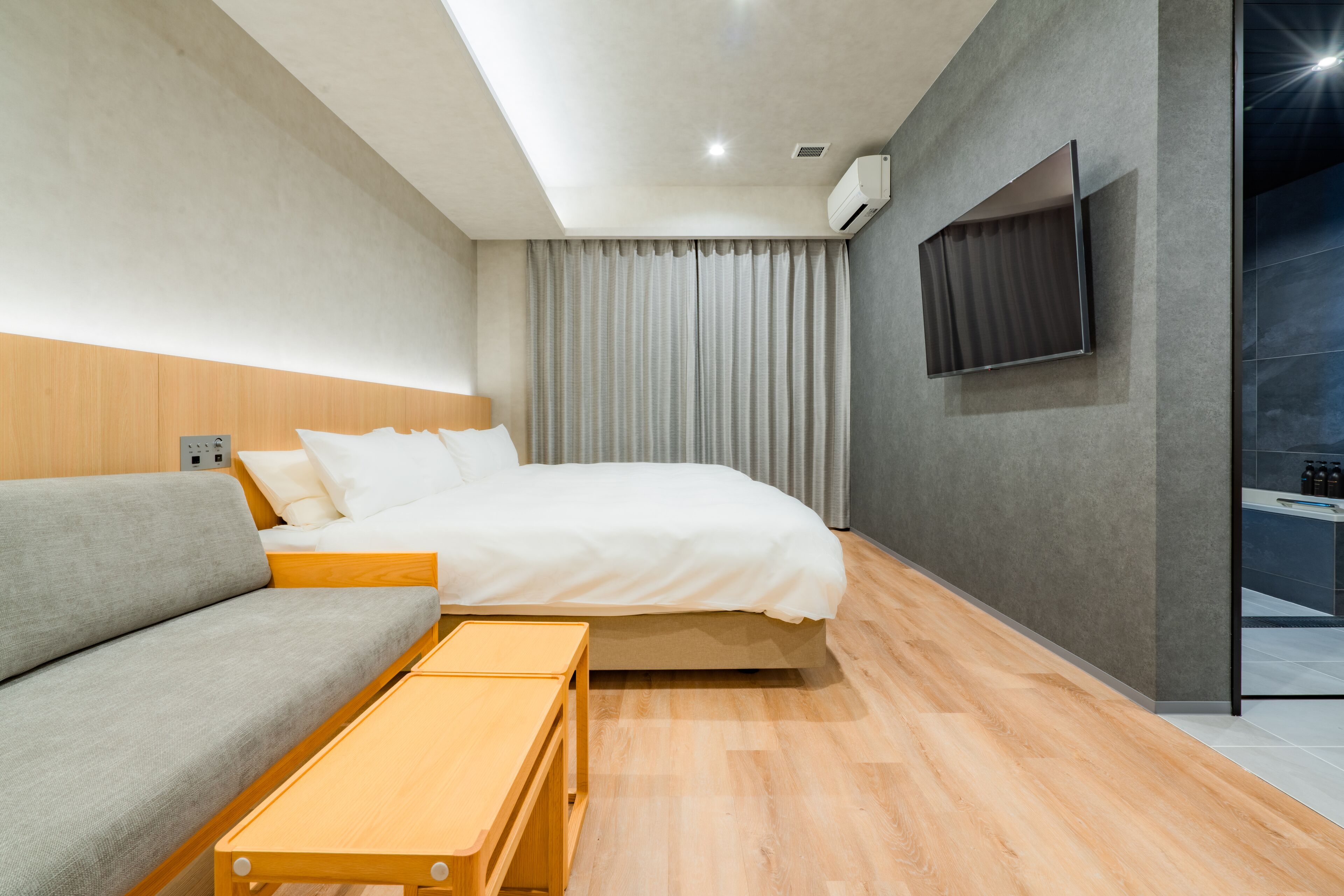 A modern hotel room with a bed, sofa, and a small table.