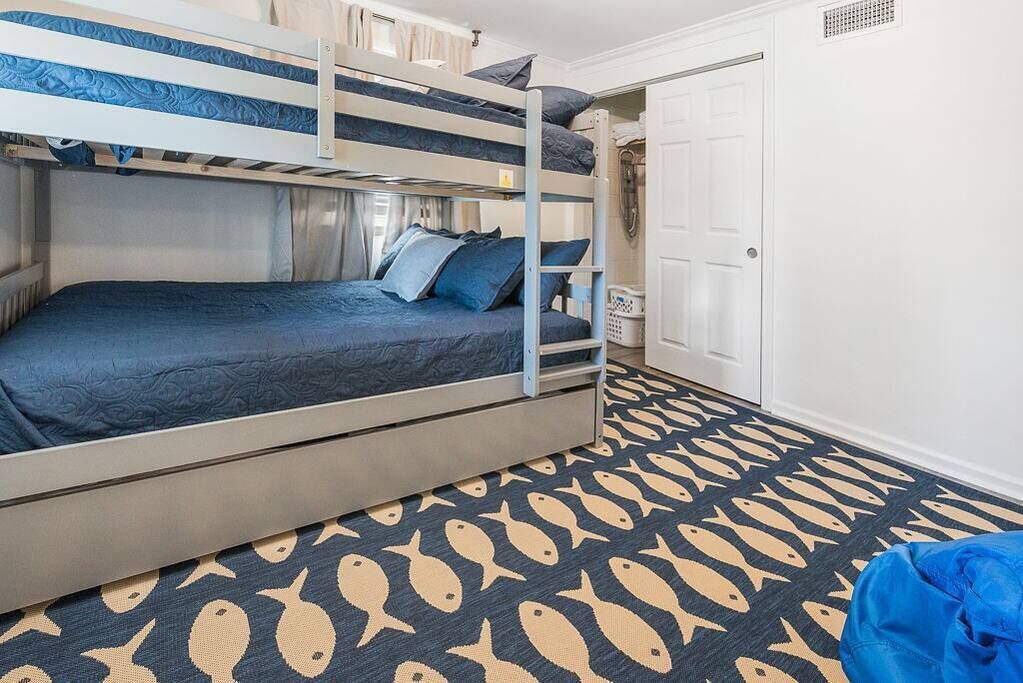 A bunk bed room with a patterned carpet and a white door.