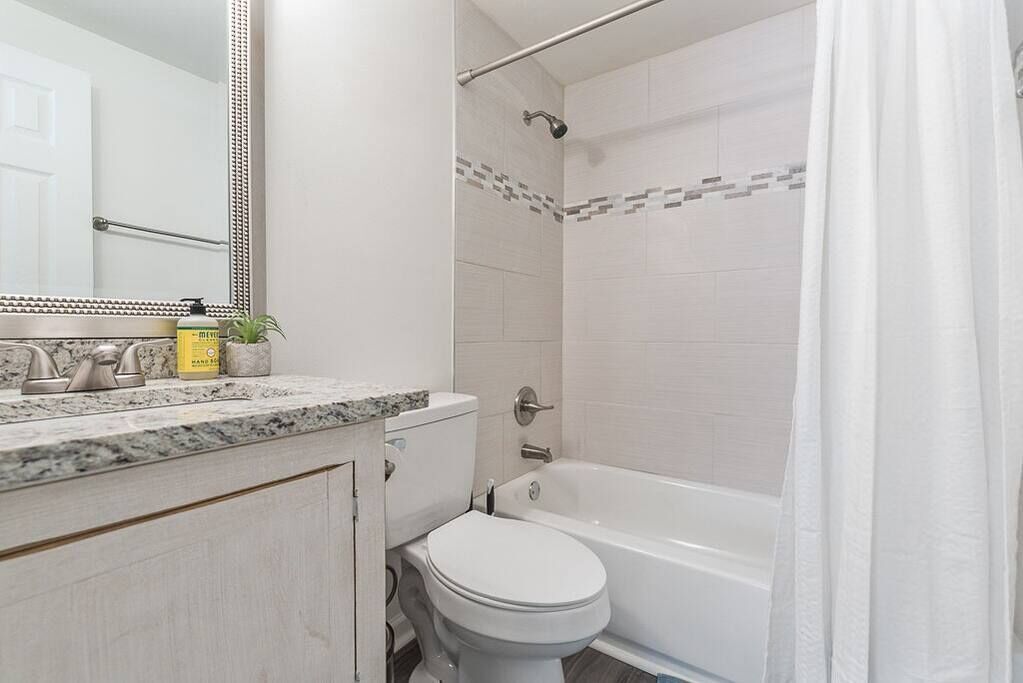 Une salle de bain avec des toilettes blanches, une baignoire et une douche avec un rideau.