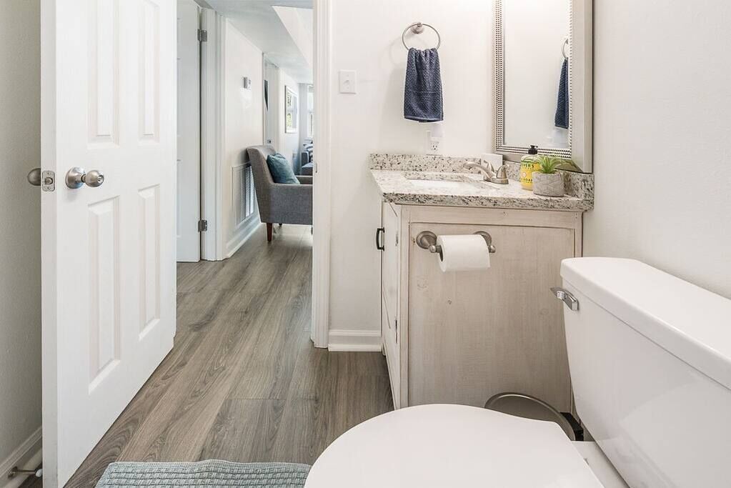 A bathroom with a toilet, sink, and mirror.