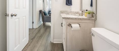 A bathroom with a toilet, sink, and mirror.