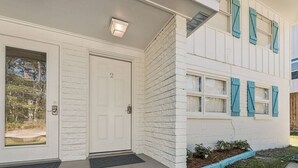 A two-story house with a white exterior, a front door with a number "2", and a small porch with a doormat.