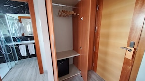A walk-in closet with a wooden door, a hanging rack, and a shelf unit. - Hotel Marqués de Aguilar (Aguilar de Campoo)