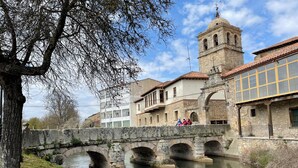 A stone bridge over a calm river, with historic buildings and a bell tower in the background. - Hotel Marqués de Aguilar (Aguilar de Campoo)