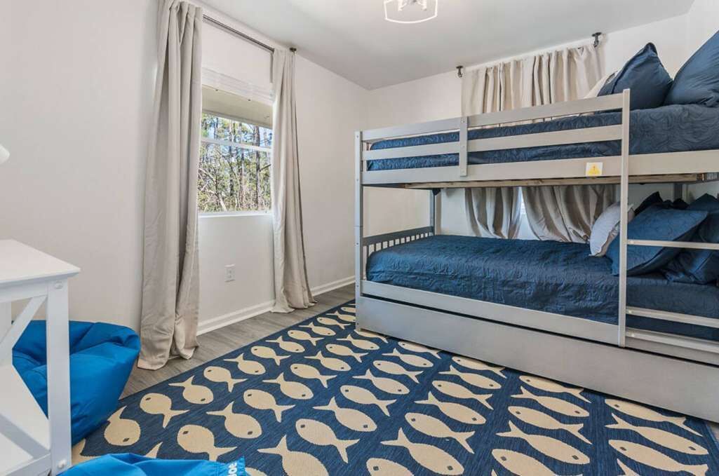 Una camera con un letto a castello, una finestra, tende e un pavimento decorato.