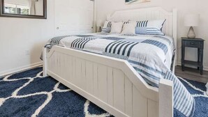 Un dormitorio con cama, mesita de noche, espejo y puerta.