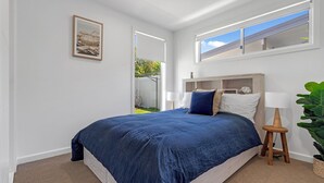 A bedroom with a large bed, a nightstand, a lamp, and a window with blinds. - Ilanga Jervis Bay-Heated Pool (Huskisson)