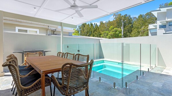 An outdoor dining area with a pool, wicker furniture, and a modern architectural design. - Ilanga Jervis Bay-Heated Pool (Huskisson)