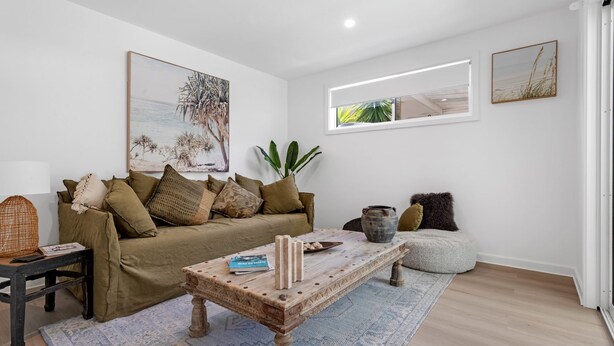 A living room with a wooden coffee table, a sofa with cushions, a potted plant, and artwork on the walls. - Ilanga Jervis Bay-Heated Pool (Huskisson)