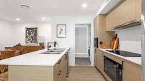 A modern kitchen with a central island, wooden cabinets, and a built-in oven. - Ilanga Jervis Bay-Heated Pool (Huskisson)