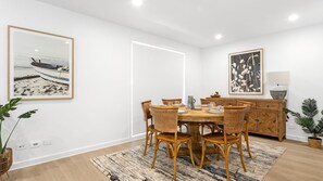 A dining area with a wooden table, wicker chairs, a buffet cabinet, and framed artwork on the walls. - Ilanga Jervis Bay-Heated Pool (Huskisson)