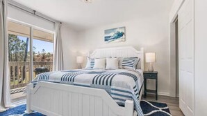 A bedroom with a bed, two bedside tables, a ceiling light, a window with curtains, and a painting on the wall.