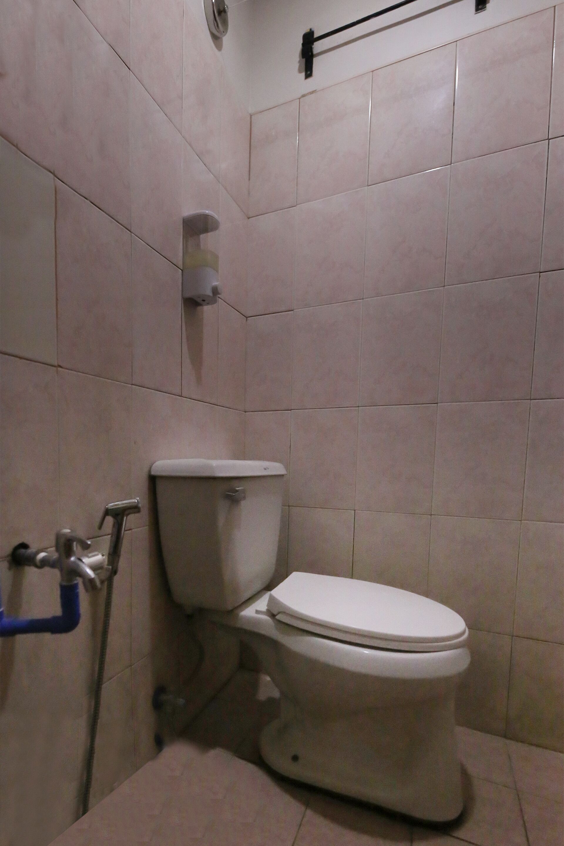 A bathroom with a toilet, a hand dryer, and a towel rack.