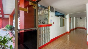 A hallway with a glass door, tiled floor, and red accents. - Busline Apartelle (Quezon City)