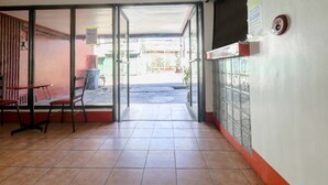 An interior corridor with a tiled floor, a glass door leading outside, and a red bench. - Busline Apartelle (Quezon City)