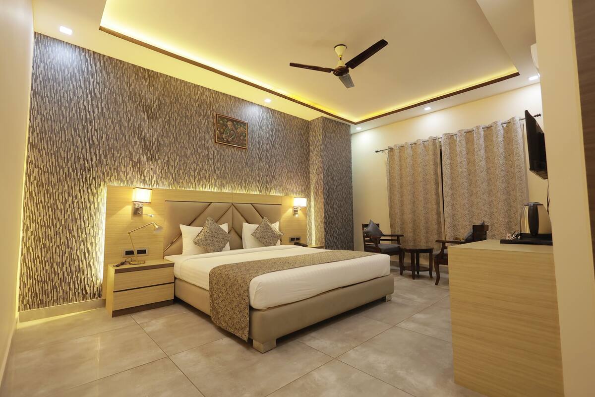 A modern hotel room with a large bed, bedside lamps, a desk, and a ceiling fan.