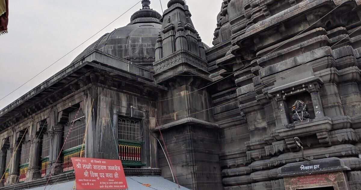A temple with intricate stone carvings and a signboard in a foreign language.