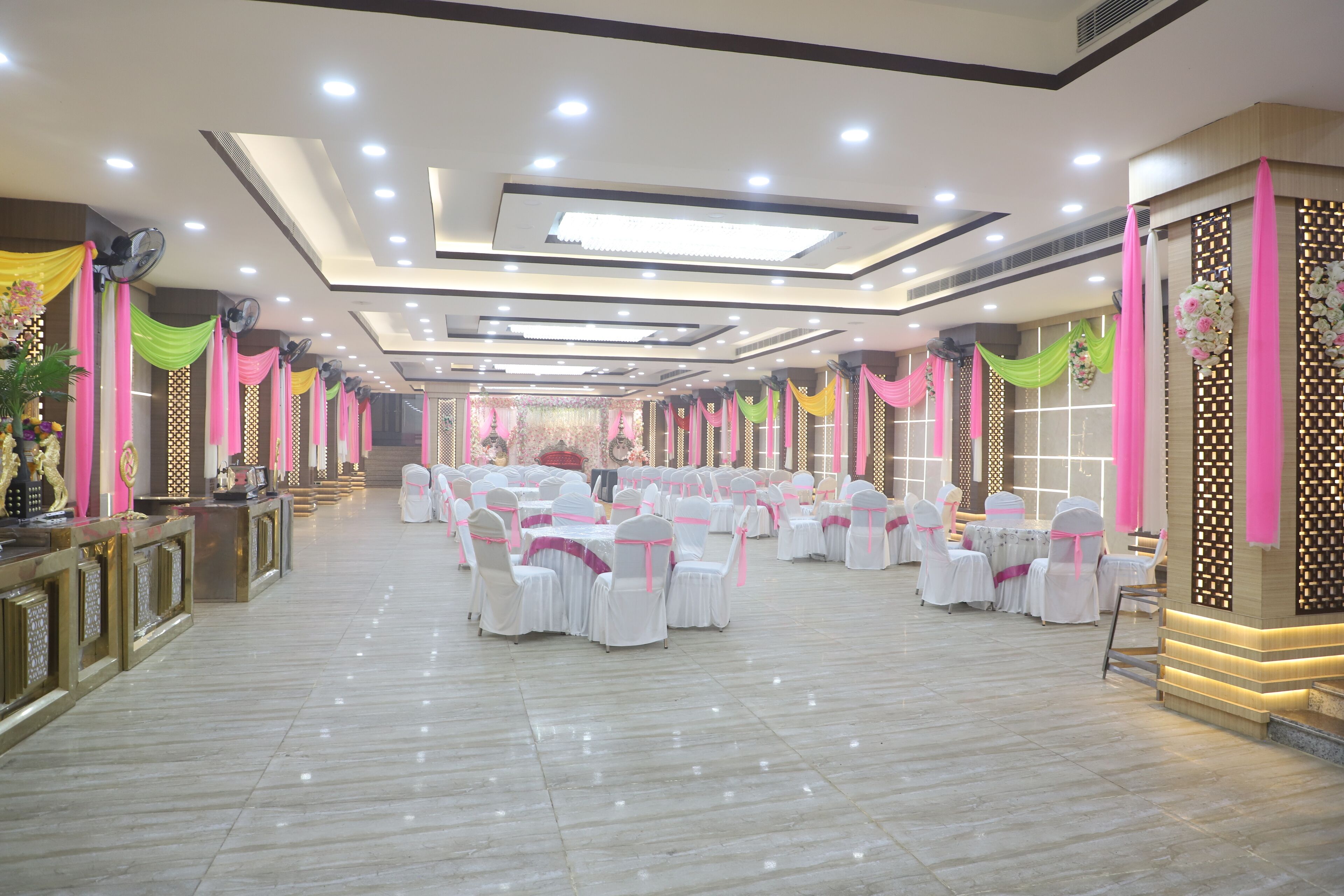 Un amplio salón de banquetes con varias mesas redondas y sillas, equipado con ventiladores de techo e iluminación empotrada.