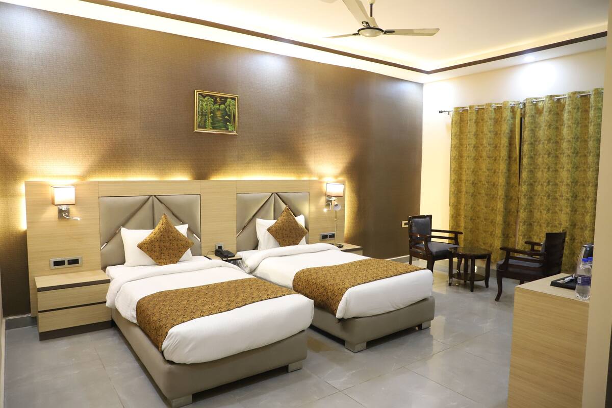 A hotel room with two beds, a desk, and a chair.