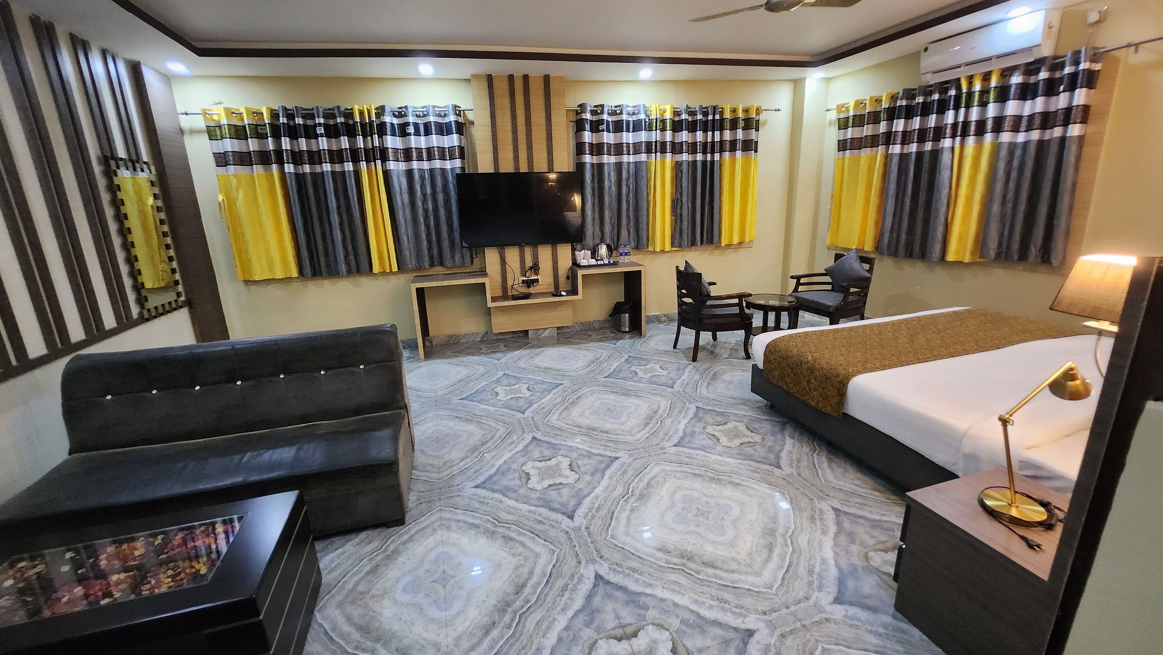 Una habitación de hotel con una cama, un escritorio, una silla, un sofá y un televisor.