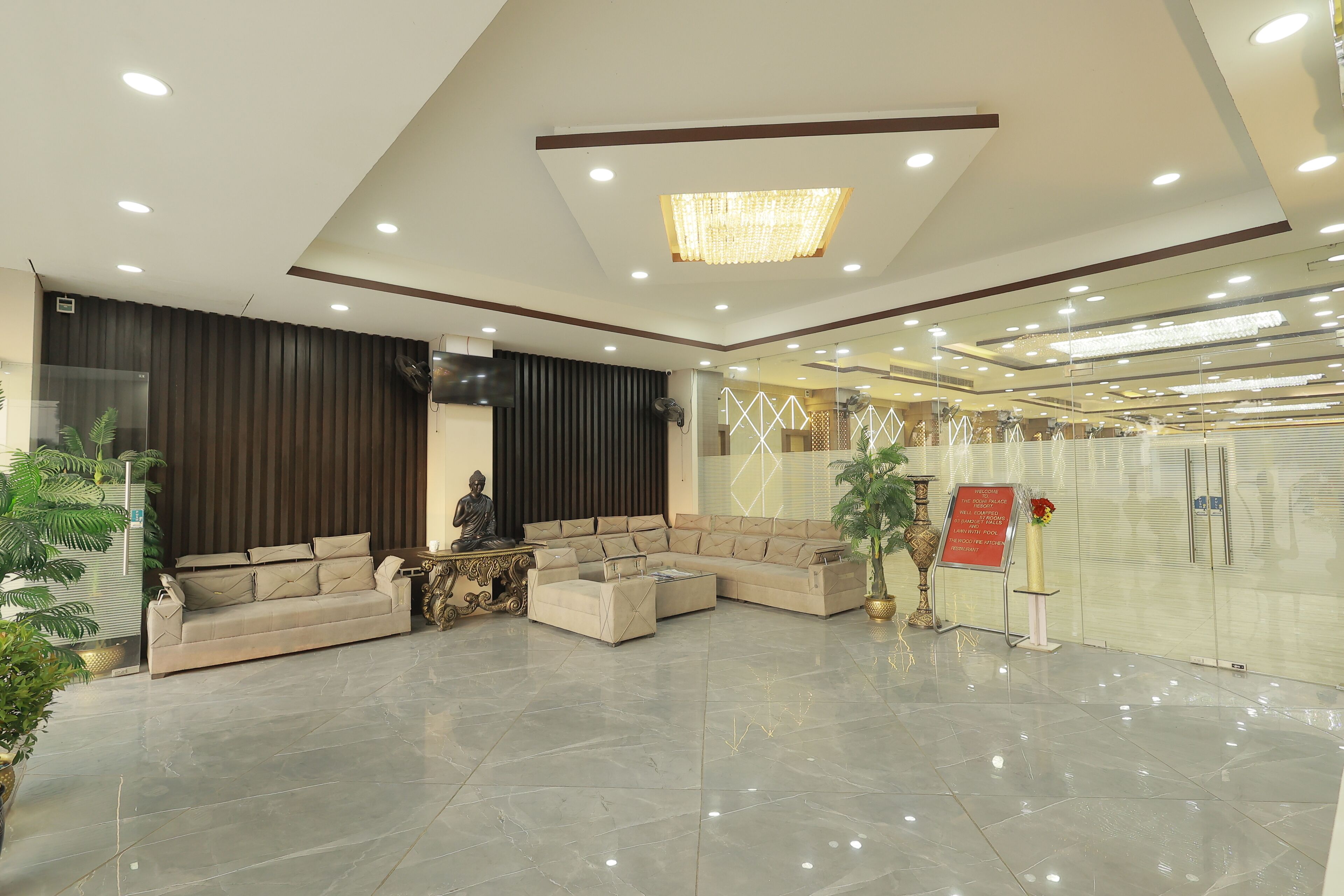 A modern lobby with a sectional sofa, a decorative Buddha statue, and a chandelier.
