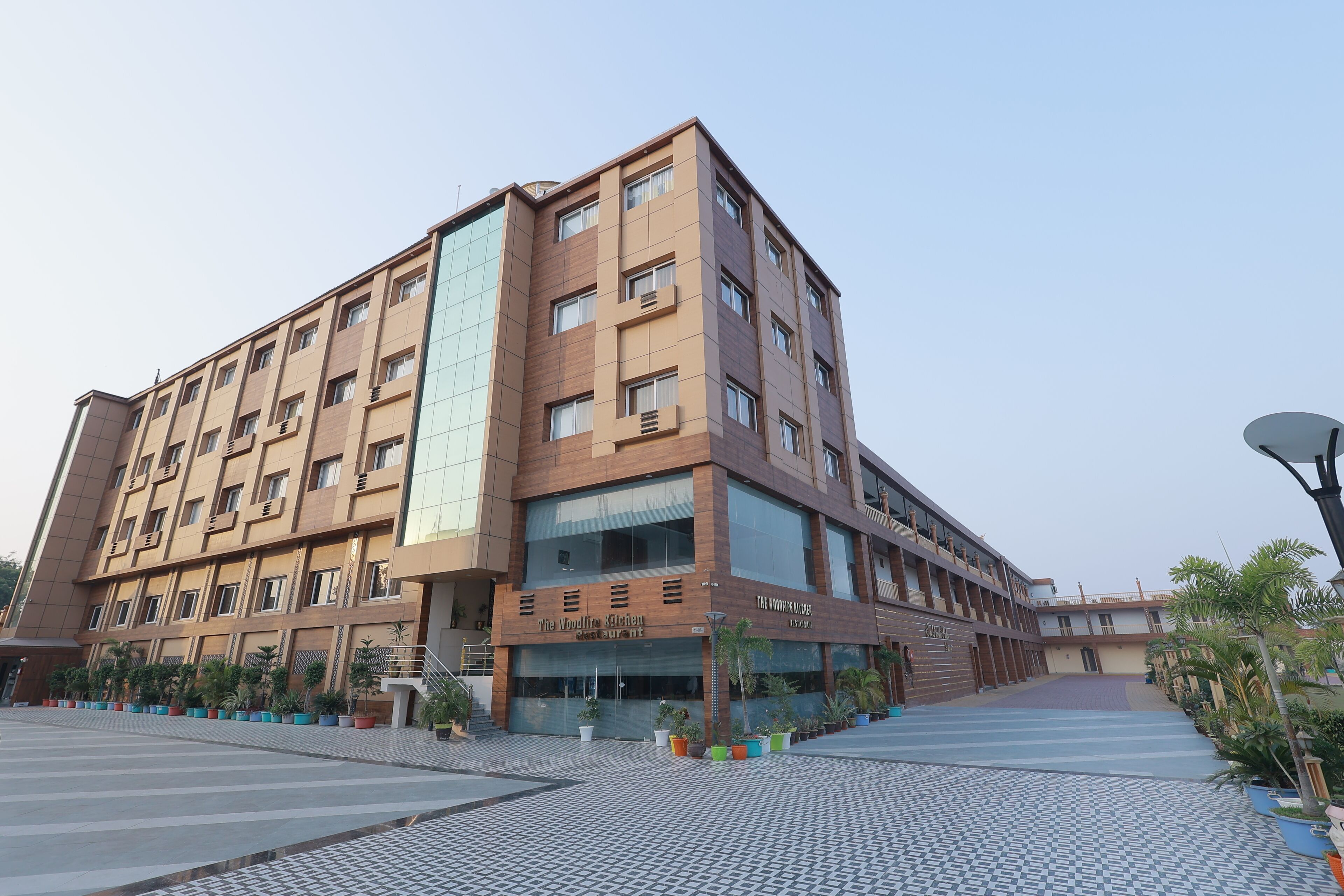 A multi-story building with a modern design, featuring a ground-level restaurant named "The Woodfire Kitchen."