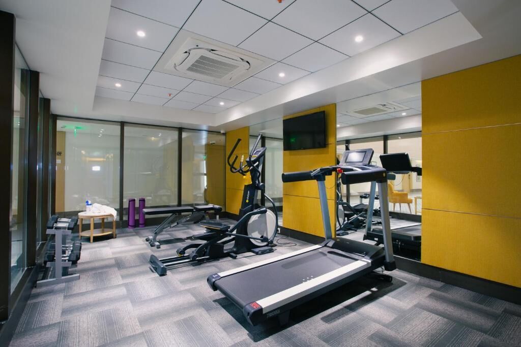 A modern gym with treadmills, elliptical machines, and weight stations.