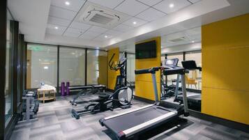 A modern gym with treadmills, elliptical machines, and weight stations.