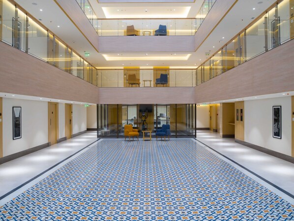 A spacious atrium with a patterned floor, glass railings, and seating areas.