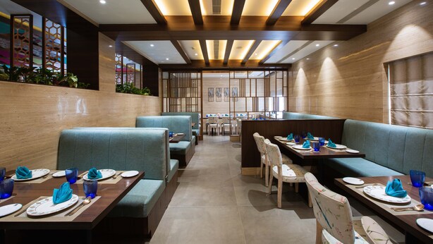 Un restaurante con cabinas y mesas, vigas de madera en el techo y suelo de baldosas.