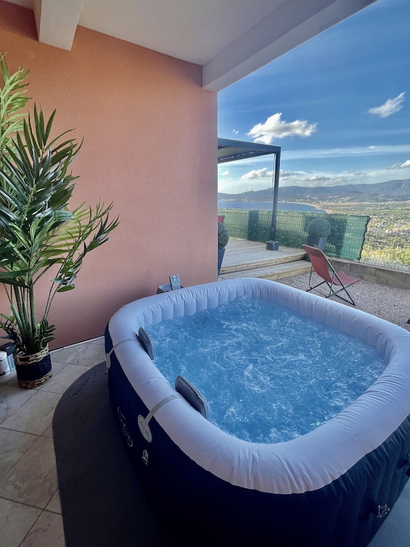 A hot tub on a balcony with a view of a lake and mountains.