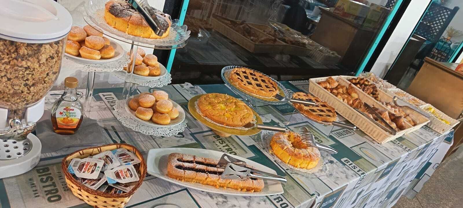 A buffet table with various baked goods and a bottle of syrup.