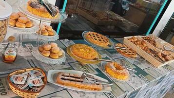 A buffet table with various baked goods and a bottle of syrup.