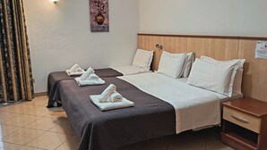 Une chambre d’hôtel avec deux lits, une tête de lit en bois, une table de chevet et un panneau fixé au mur.